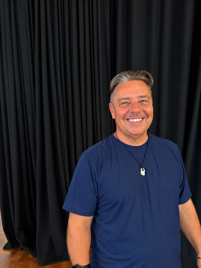 Smiling Man Against Dark Curtains 768x1024